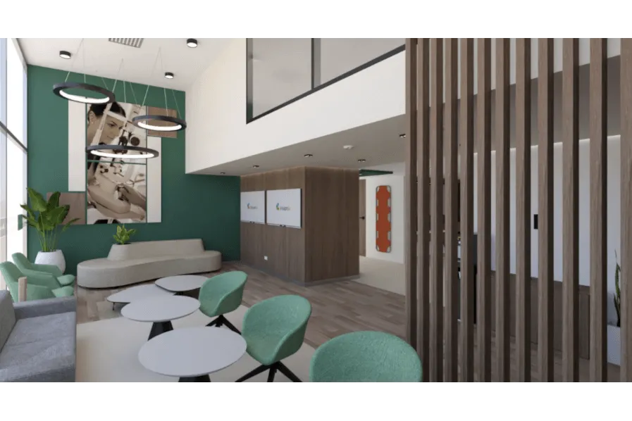 Hay una sala de espera con tonos blancos y verdes, se ve amplia, iluminada, con sillas, plantas y sofás, para que se pueda esperar de manera agradable